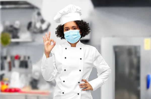 Kobieta szef kuchni w masce medycznej i toque pokazuje ok — Zdjęcie stockowe