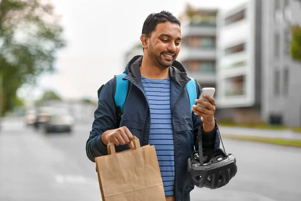Repartidor con comida para llevar en bolsa y teléfono — Foto de Stock