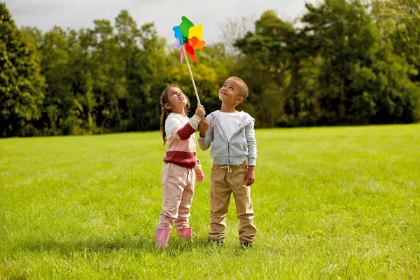 Happy children playing with pinwheel at park — Stock Photo, Image