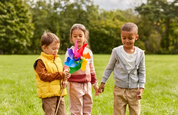 Glückliche Kinder mit Windrad haben Spaß im Park — Stockfoto