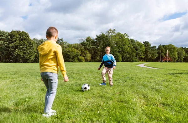 Niños pequeños felices con pelota jugando al fútbol en el parque — Foto de Stock