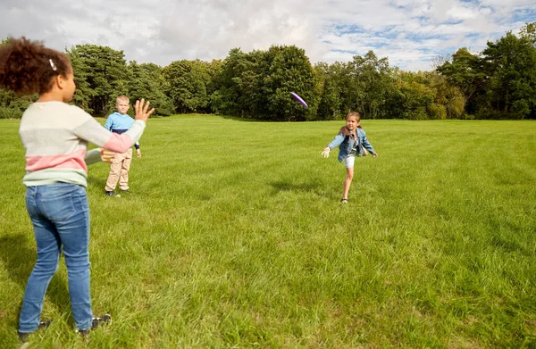 Niños felices jugando con disco volador en el parque —  Fotos de Stock