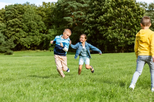 Glückliche Kinder spielen und rennen im Park — Stockfoto