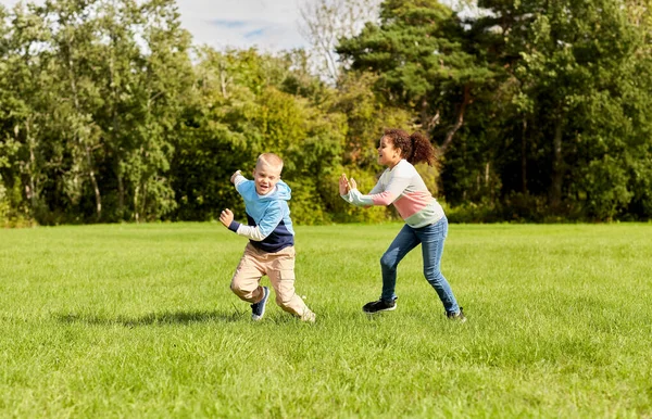 Glückliche Kinder spielen und rennen im Park — Stockfoto