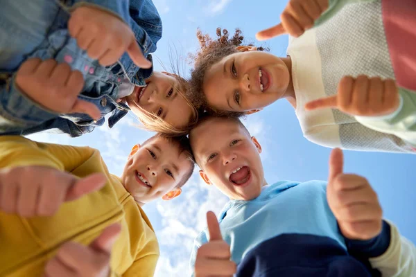 Happy children showing thumbs up outdoors — стоковое фото