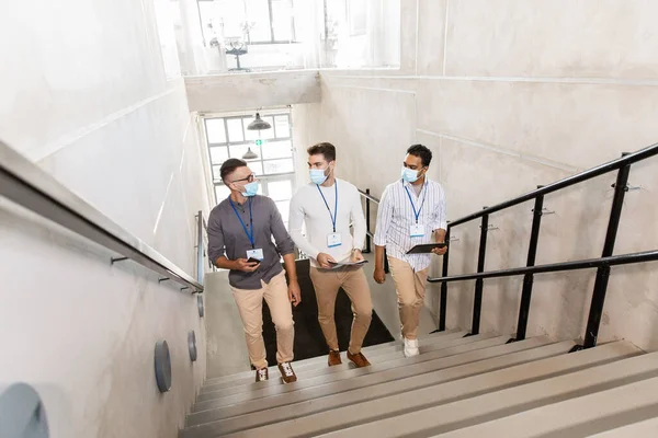 Affärsmän i masker med namnbrickor går upp — Stockfoto