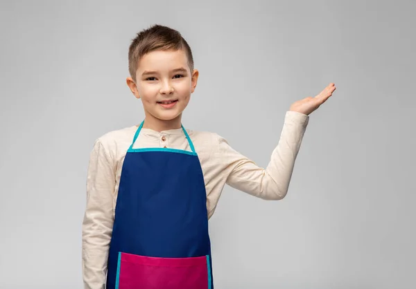 Liten pojke i förkläde håller något på handen — Stockfoto