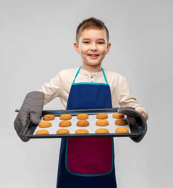 Menino em avental segurando assadeira com biscoitos — Fotografia de Stock