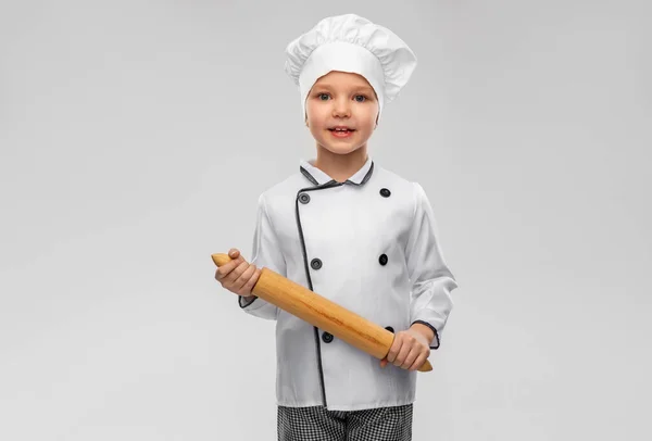 Happy little girl in chefs toque with rolling pin — Fotografia de Stock