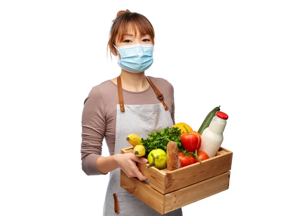 Vrouwelijke chef-kok in masker met voedsel in houten doos — Stockfoto