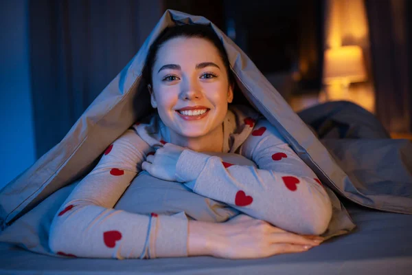 Счастливая девочка-подросток, лежащая под одеялом в постели — стоковое фото