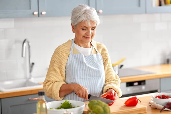 Щаслива жінка нарізає червоний перець на кухні — стокове фото