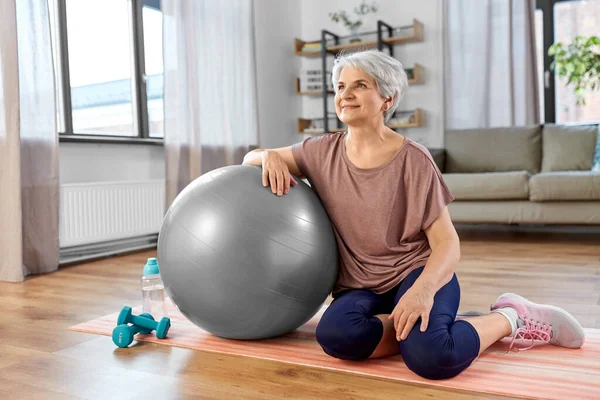 Gülümseyen yaşlı kadın evde egzersiz topuyla — Stok fotoğraf