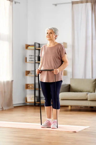 Senior woman exercising with elastic band at home — Stock Photo, Image