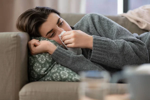 Sad crying woman with tissue lying on sofa at home — ストック写真