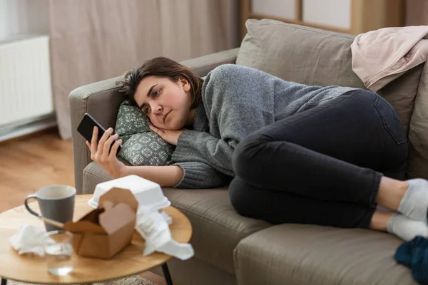 Stressed woman with smartphone on sofa at home — Foto de Stock