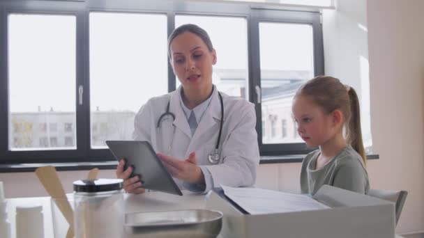 Dokter menunjukkan tablet pc ke gadis kecil di klinik — Stok Video