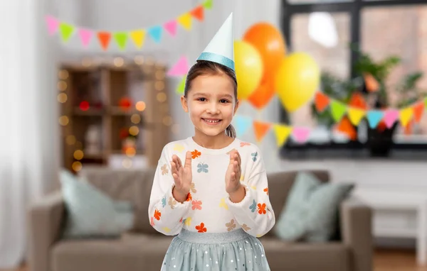 Feliz niña en cumpleaños fiesta sombrero aplaudiendo —  Fotos de Stock