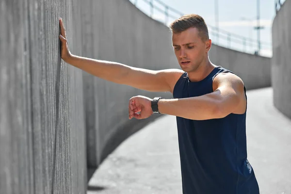 Young man with fitness tracker on city street — Stock Photo, Image