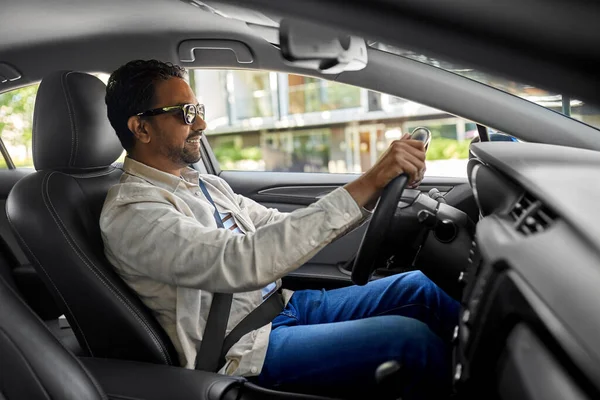 Усміхнений індійський чоловік в сонцезахисних окулярах водіння автомобіля — стокове фото