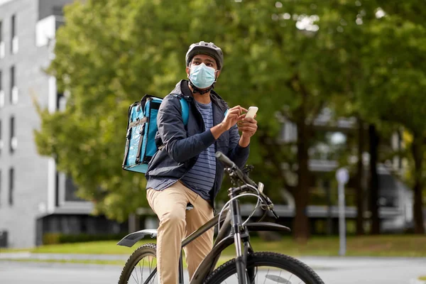 戴口罩的送货员，带着手机骑自行车 — 图库照片