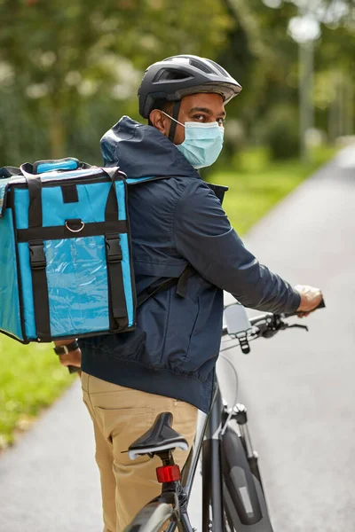 Доставщик еды в маске с сумкой и велосипедом — стоковое фото