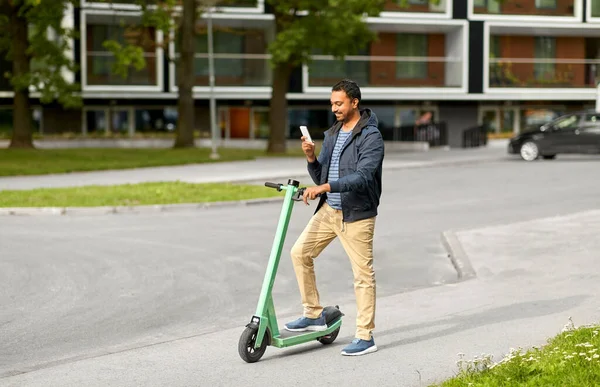 Hombre con smartphone y scooter eléctrico en la ciudad —  Fotos de Stock