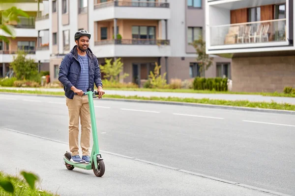 Hombre en casco a caballo scooter eléctrico en la calle —  Fotos de Stock