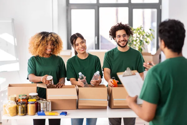 Voluntarios felices empacando comida en cajas de donaciones —  Fotos de Stock