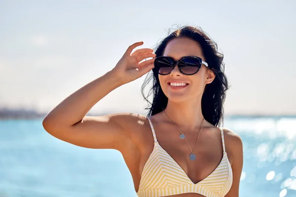Glimlachende jonge vrouw in zonnebril op zomerstrand — Stockfoto