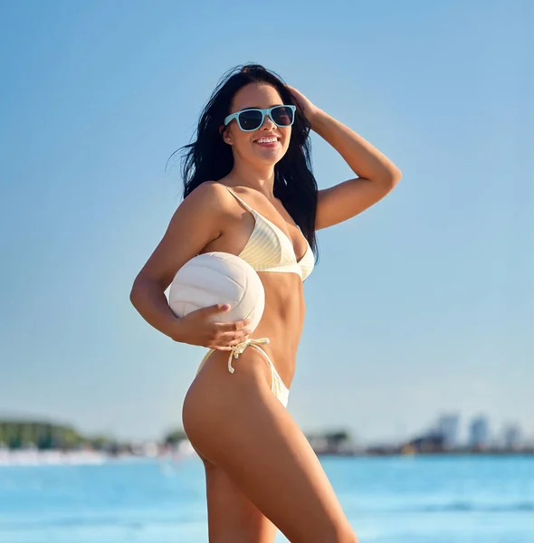 Kobieta w bikini pozuje z siatkówką na plaży — Zdjęcie stockowe
