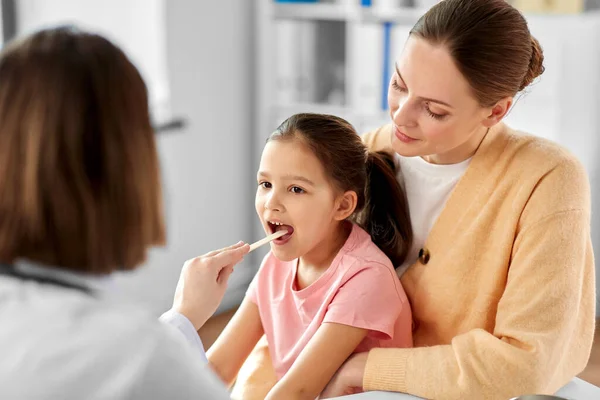 Mujer médico chequeo niñas garganta en clínica —  Fotos de Stock