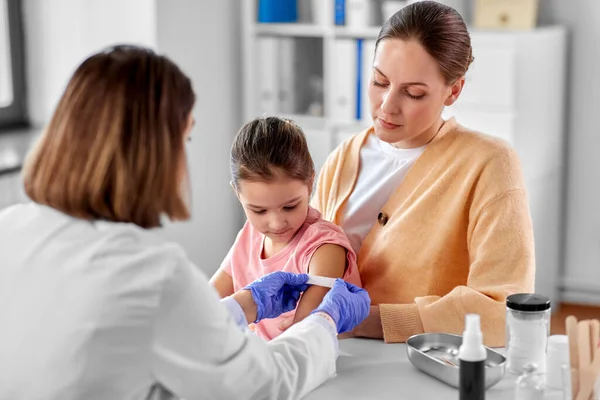 Doctor sticking patch to childs arm at clinic — Zdjęcie stockowe