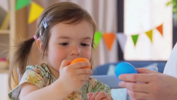 Дівчинка і мати б'ють великодні яйця вдома — стокове відео