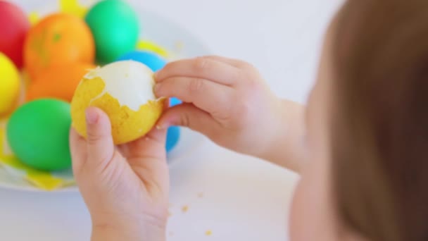 Baby girl peeling easter egg from shell at home — Video
