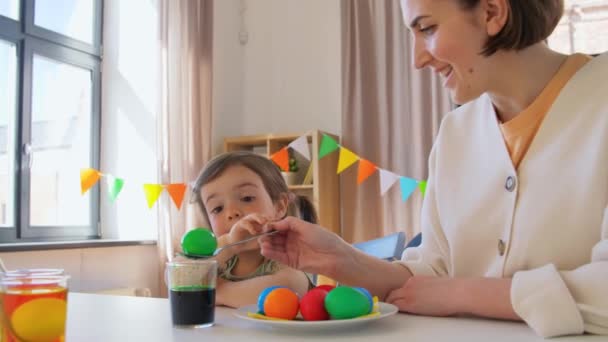 Mother with child dyeing easter eggs at home — Stockvideo