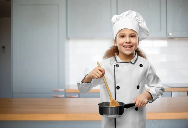 Счастливая девушка в токе шеф-поваров с ложкой и кастрюлей — стоковое фото