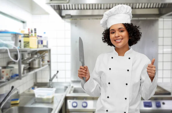 Chef femenino en toque con cuchillo mostrando los pulgares hacia arriba —  Fotos de Stock