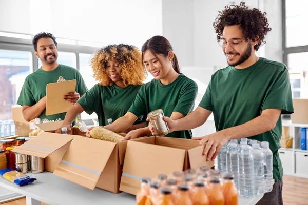 Gelukkige vrijwilligers die voedsel in donatiedozen verpakken — Stockfoto