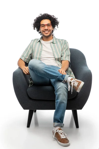 Счастливый улыбающийся молодой человек, сидящий в кресле — стоковое фото