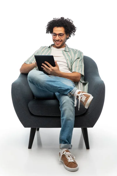 Giovane uomo sorridente con tablet pc seduto in sedia — Foto Stock