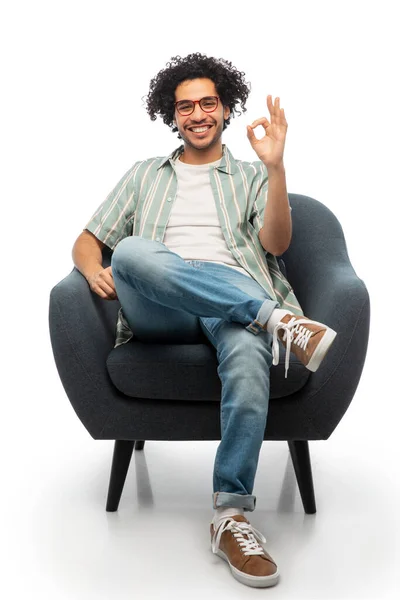Homem feliz sentado na cadeira e mostrando ok gesto — Fotografia de Stock
