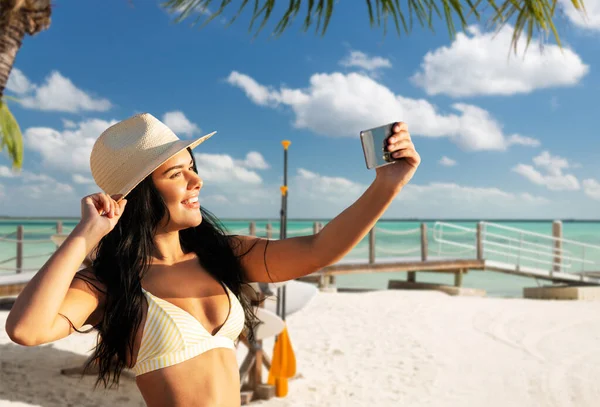 Donna sorridente in bikini scattare selfie sulla spiaggia — Foto Stock
