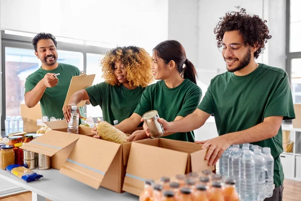 Voluntarios felices empacando comida en cajas de donaciones —  Fotos de Stock