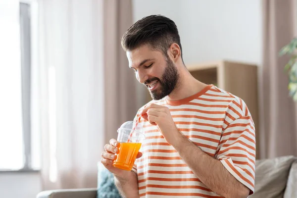Smiling man drinking orange juice at home — Stok fotoğraf