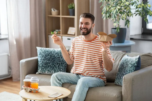 Smiling man eating takeaway food at home — Stockfoto
