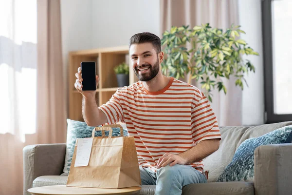 Hombre sonriente usando teléfono inteligente para la entrega de alimentos — Foto de Stock