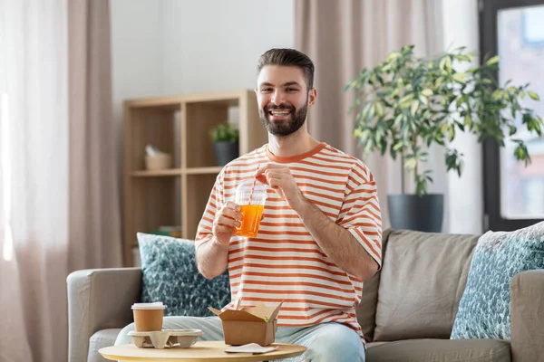 Sorrindo homem com comida takeaway e bebidas em casa — Fotografia de Stock