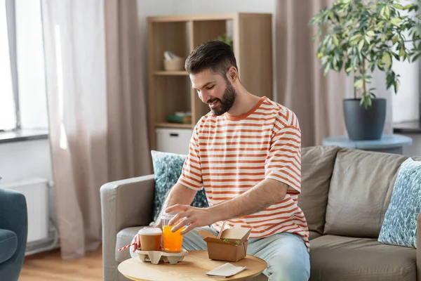Smiling man with takeaway food and drinks at home — Foto de Stock