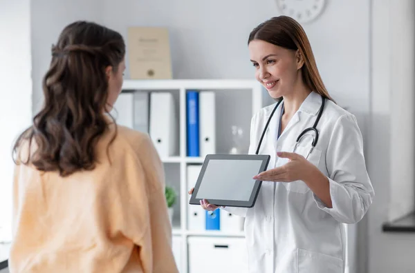 Female doctor shows tablet pc to woman at hospital — Stok fotoğraf